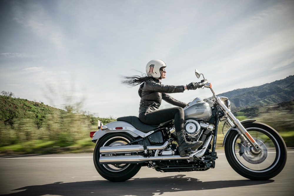 A female motorcycle rider cruising along a clean road. She is in full motorcycle gear, which is ideal for riding safety.