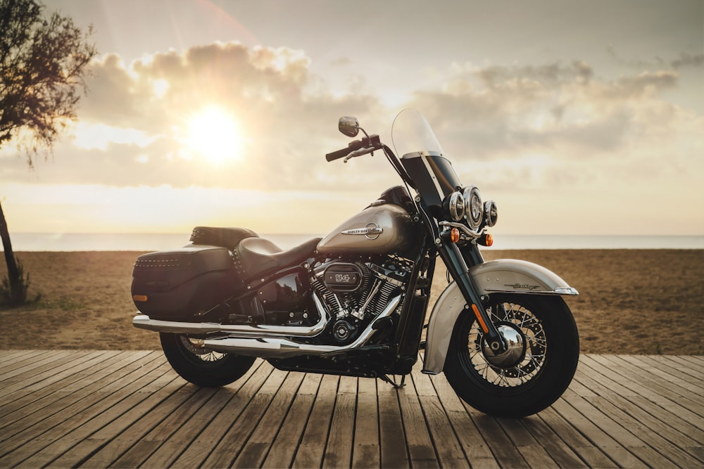 black and gray touring motorcycle on wooden dock near brown field under gray and orange skies