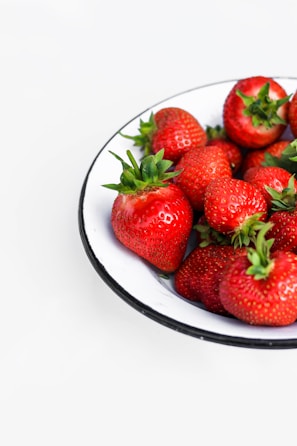 Bright red strawberries arranged neatly on a white ceramic plate