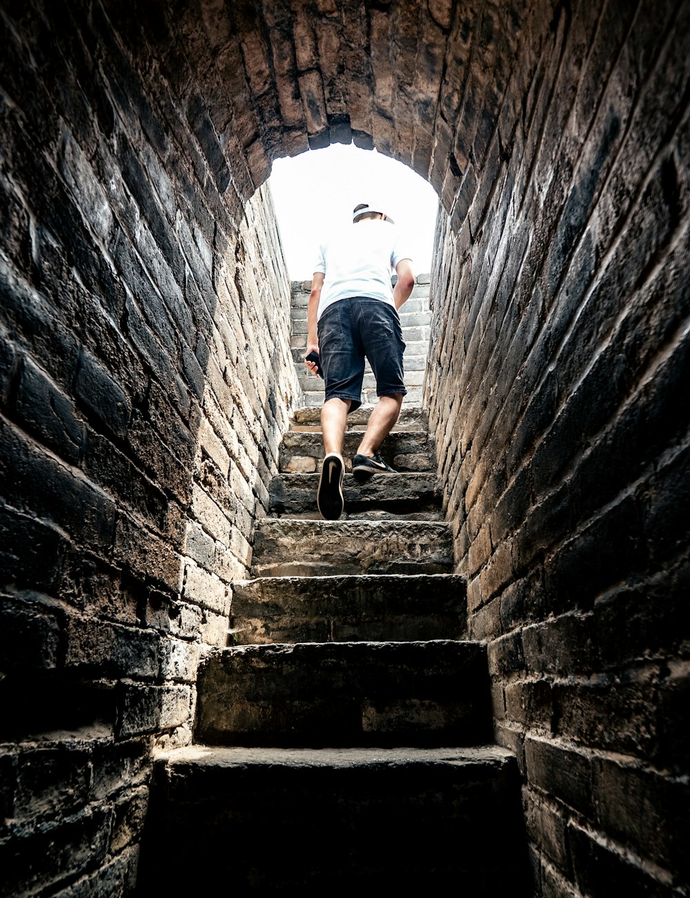 person in white t-shirt and black shorts walking outside of tunnel