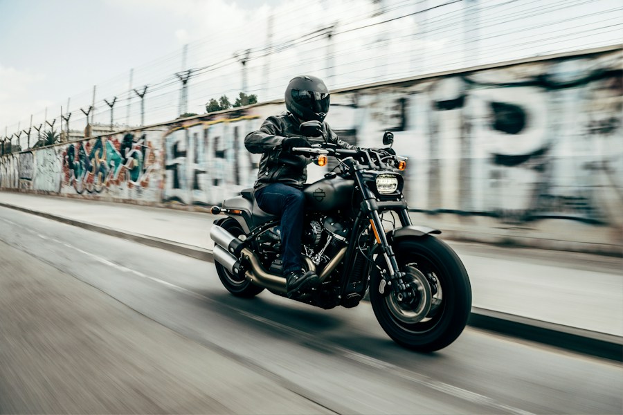 A motorcycle rider racing through a city street — the spirit of the café racer