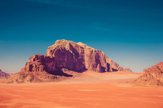 brown rock formation surrounded by sand dunes