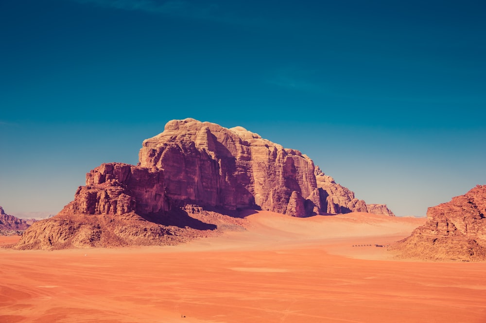 brown rock formation surrounded by sand dunes