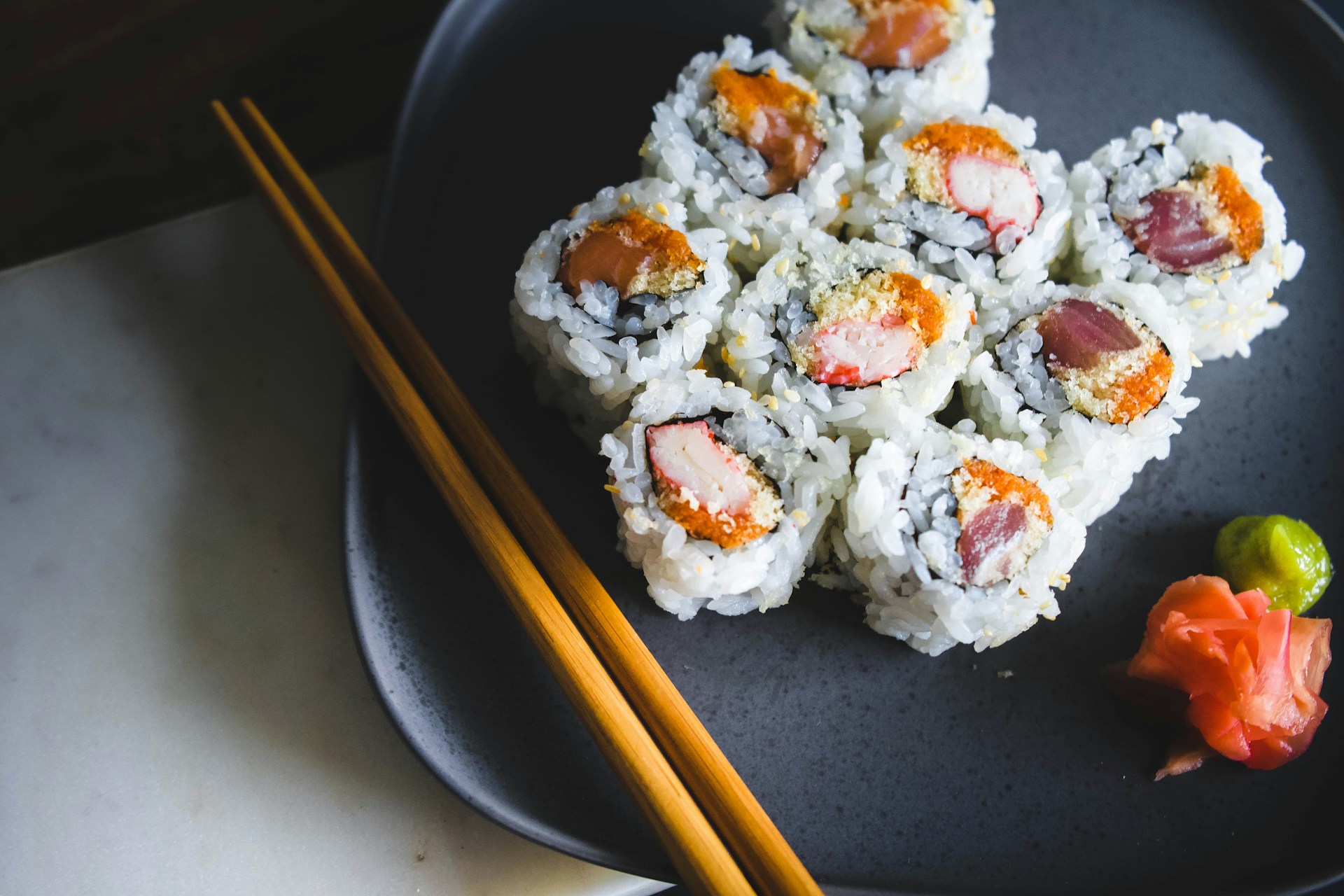A beautifully arranged sushi platter featuring fresh salmon, tuna, and avocado rolls with a side of pickled ginger and wasabi.