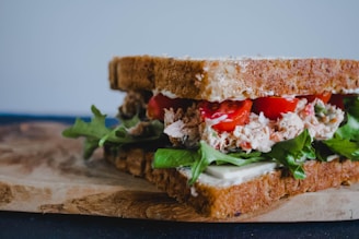 Close-up of a fresh sandwich with vegetables and bread on a wooden table.