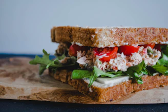 Close-up of a rustic, handmade sandwich filled with fresh ingredients on a wooden board.