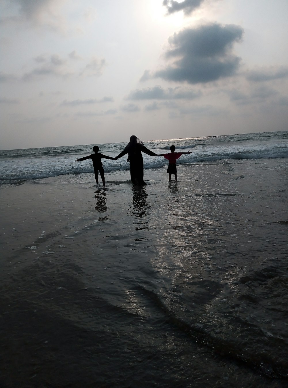 three person standing in front of shoreline