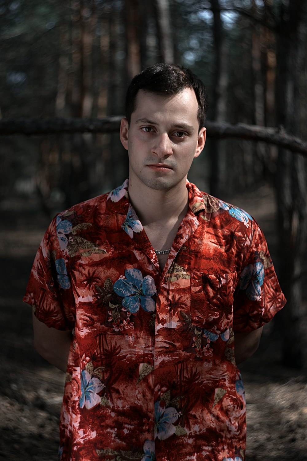 man wearing brown and blue floral short-sleeve button-up shirt at the woods