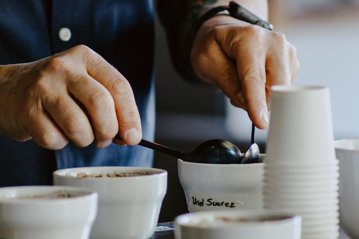 Barista's hands holding cupping spoons during a coffee tasting session