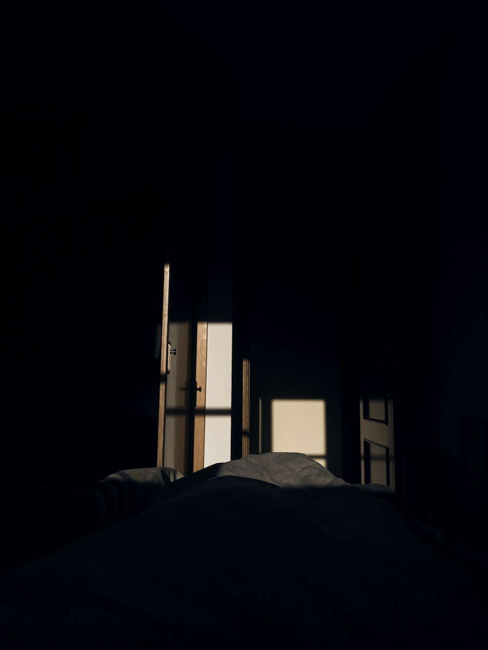 a dark room with a window and a bed