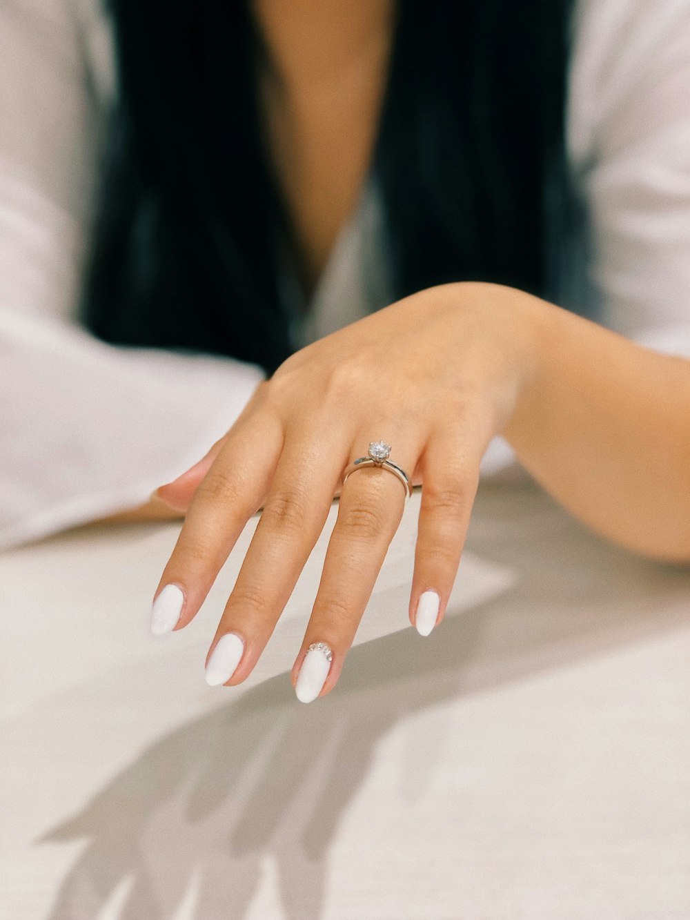 person with white nail polish on left fingers