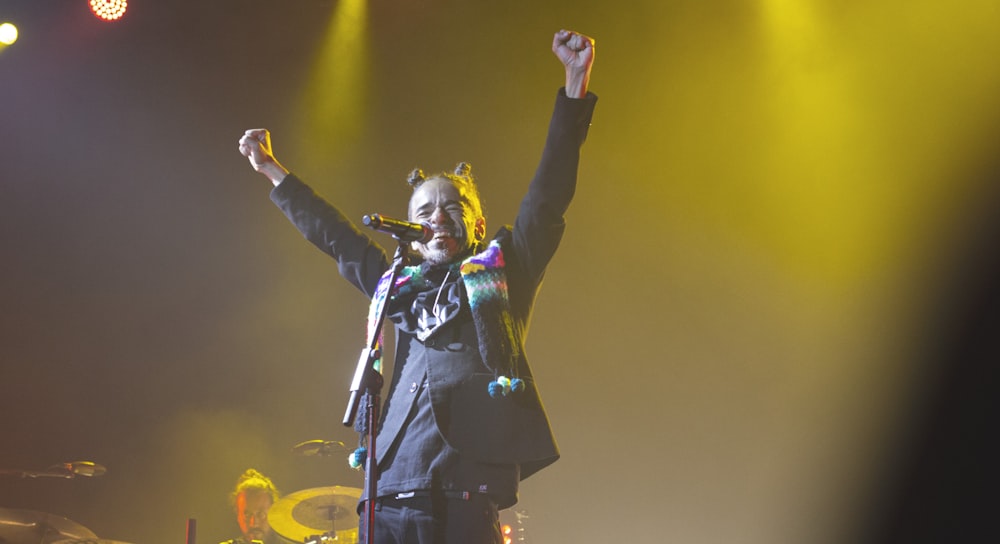 man standing and performing on stage front of microphone