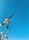 Two fishing rods are secured with their reels visible against a clear blue sky. The rods are positioned vertically and extend upwards, showcasing their sleek design and metallic components.
