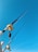 Two fishing rods are secured with their reels visible against a clear blue sky. The rods are positioned vertically and extend upwards, showcasing their sleek design and metallic components.