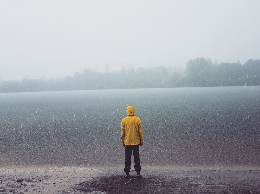 Mann steht am Ufer mit Blick auf den Ozean bei Regen