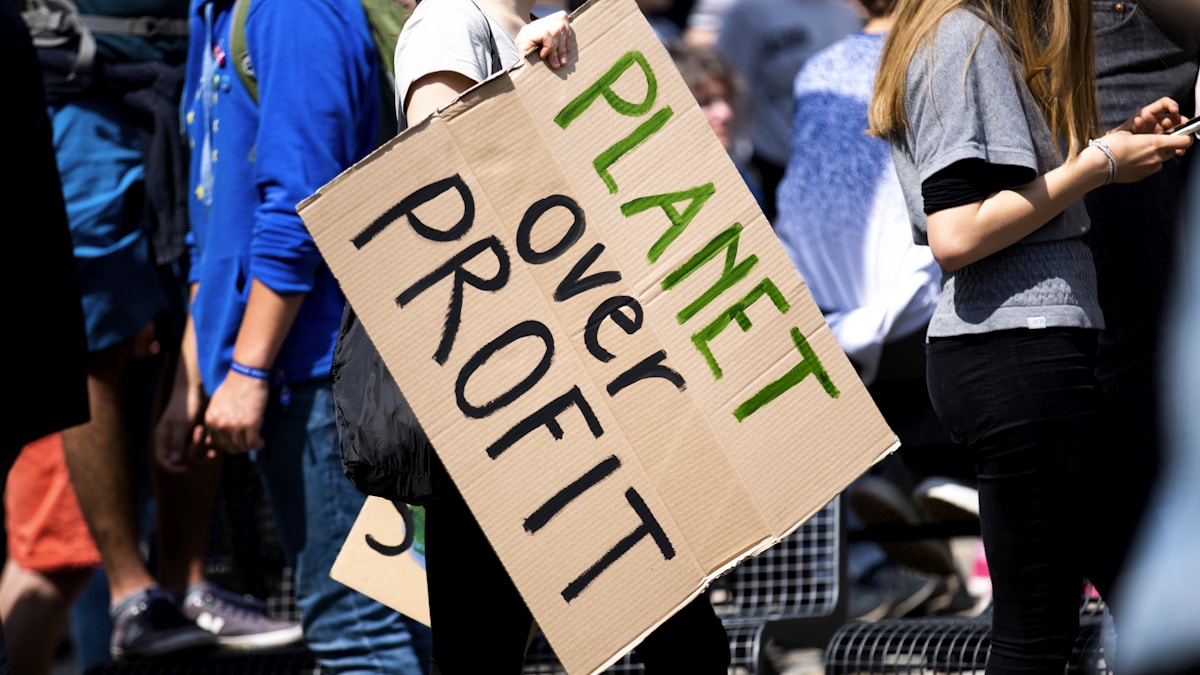 woman holding Planet over Profit placard