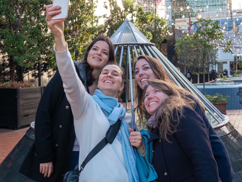 four women taking selfie near tipi tent