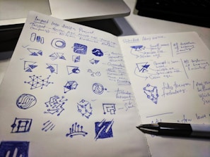 A designer sketching logo concepts on a notepad with colorful markers.