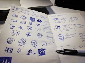 A designer sketching logo ideas on a notepad surrounded by color swatches.