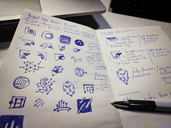 A designer sketching logo concepts on paper with colorful markers around.