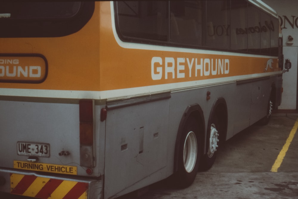 建物内に停車しているオレンジとグレーのグレイハウンドバス