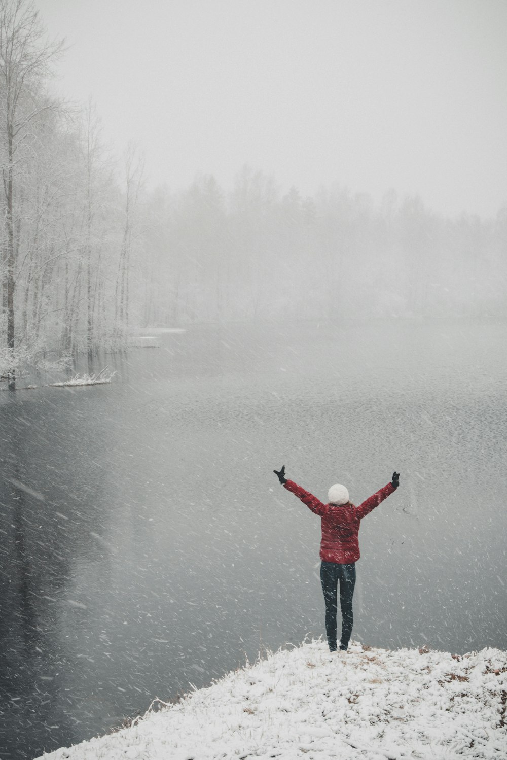 person in red jacket standing near body of water