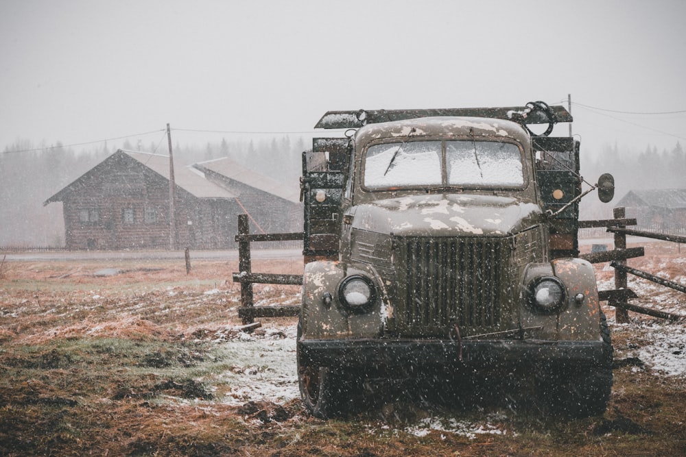 brown and grey vehicle near brown wooden fence during rain