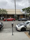 Shiny high-end sports cars lined up as part of valet parking at a bustling restaurant.
