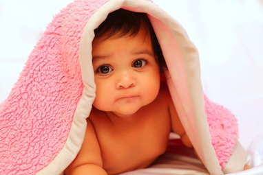 baby covered with pink fleece blanket