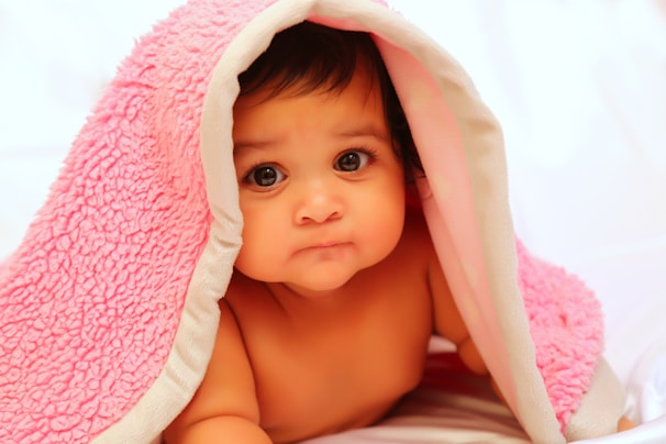 baby covered with pink fleece blanket