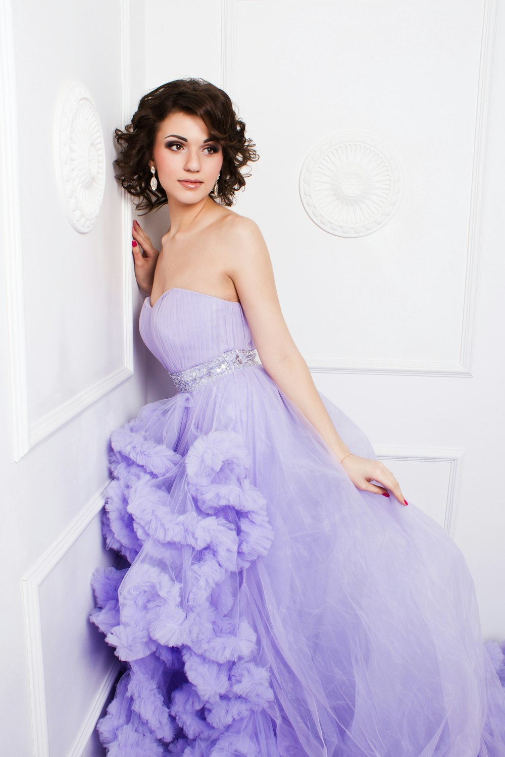 壁にもたれかかる紫色のストラップレスウェディングドレスを着た女性