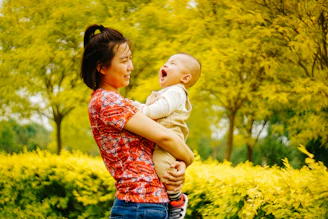 A mother and baby laughing together outdoors, with the Nurtiva app open on a tablet nearby.