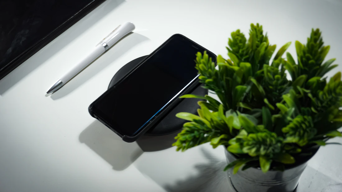 Smartphone resting on a wireless charger in a clean desk setting