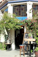The cafe’s quaint exterior framed by blooming flowers on a bright spring morning.