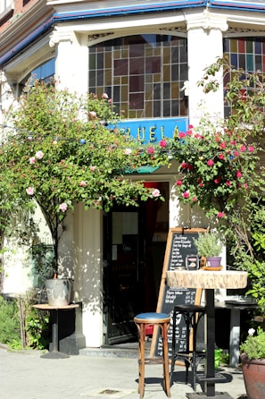 The cafe’s quaint exterior framed by blooming flowers on a bright spring morning.