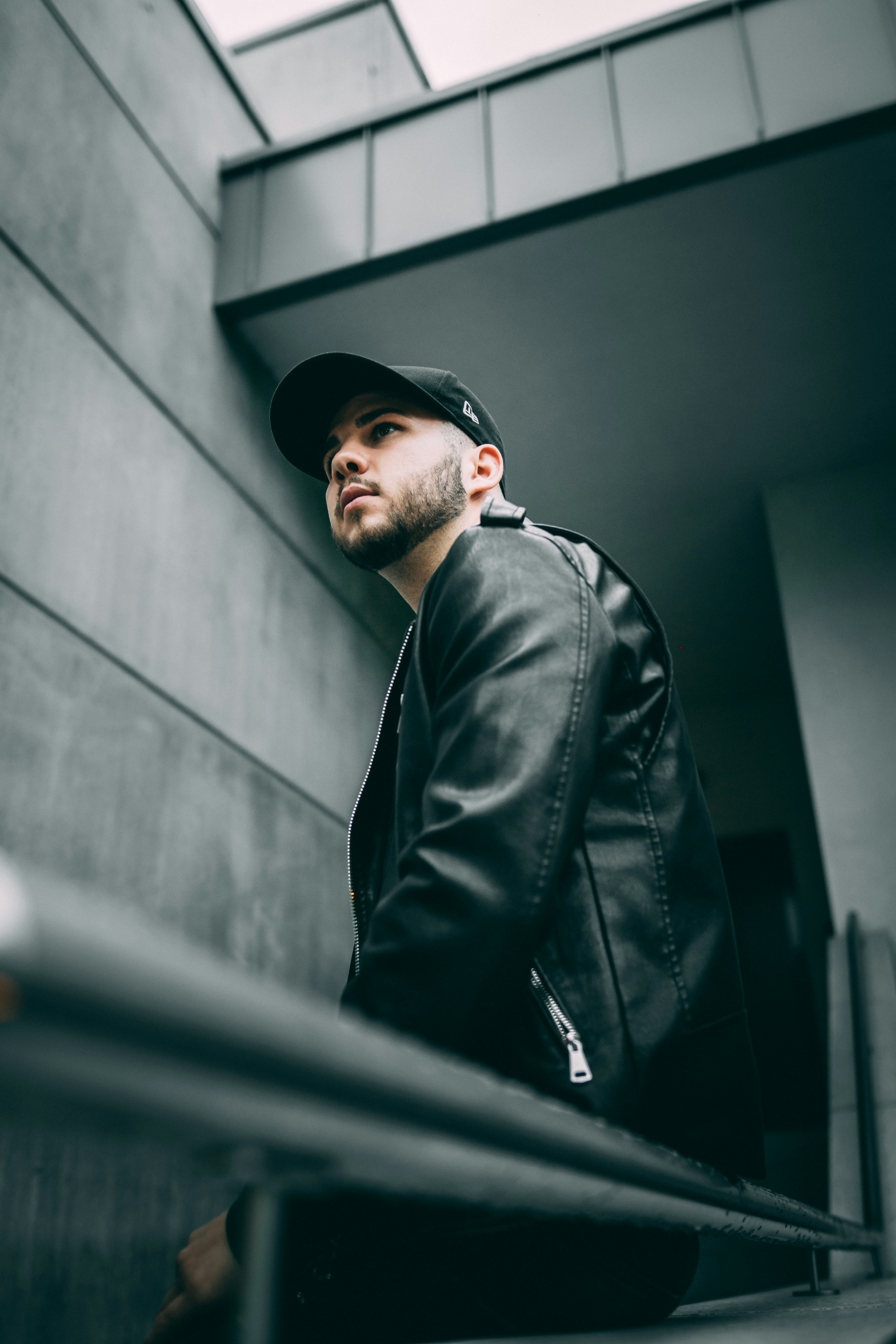 man in black leather jacket sitting on railings