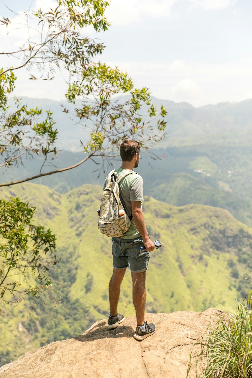 Mann steht auf Klippe mit Blick auf den Berg