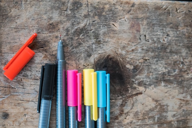 A collection of colorful pens displayed on a wooden desk.