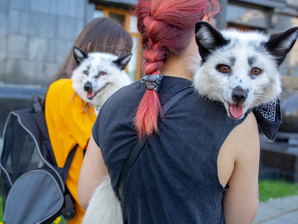 two women carrying white foxes during daytime