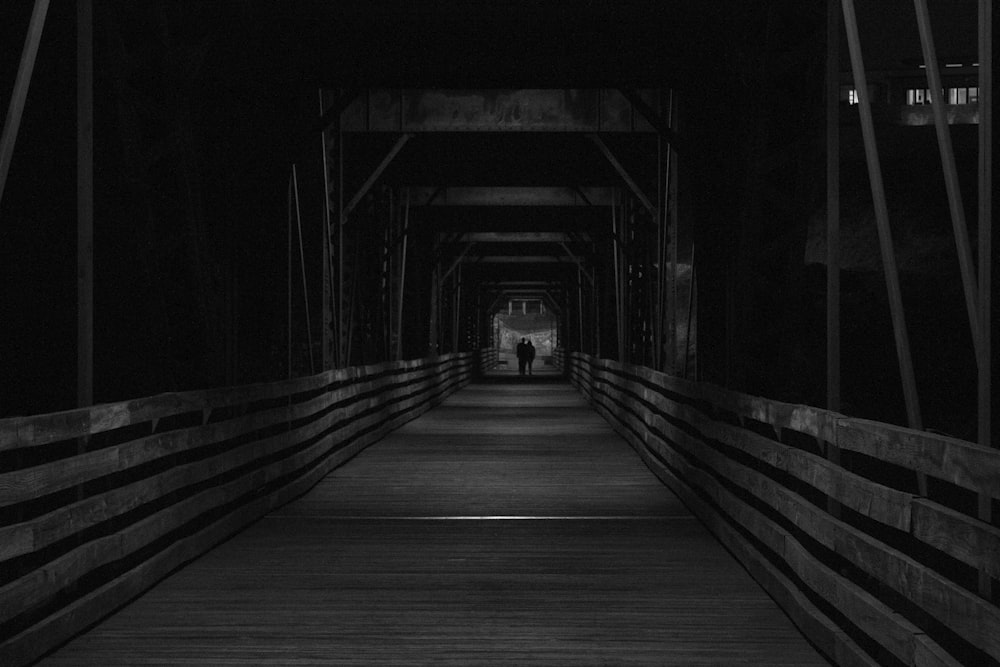 two people walking on wooden bridge