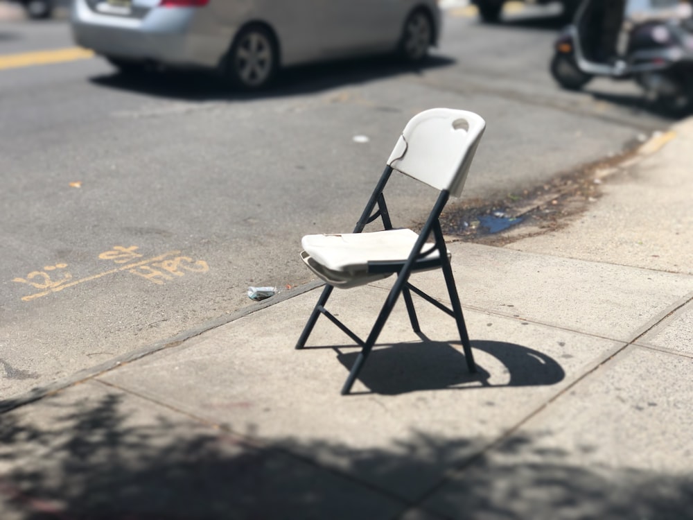 white and black folding chair on roadside during daytime