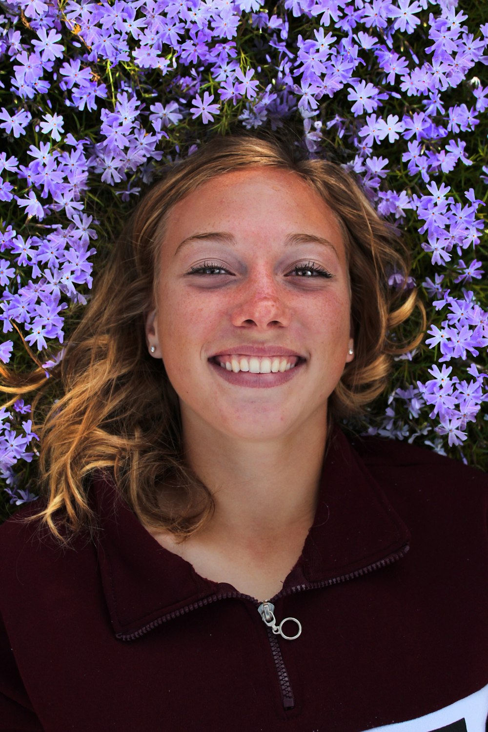 smiling woman near purple-petaled flower