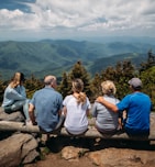 group of people sitting on rocks overlooking mountain