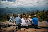 group of people sitting on rocks overlooking mountain