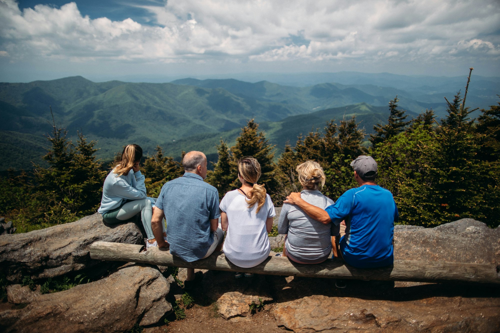 Five family members watching over the mountain valley, at the top of a mountain, relaxed