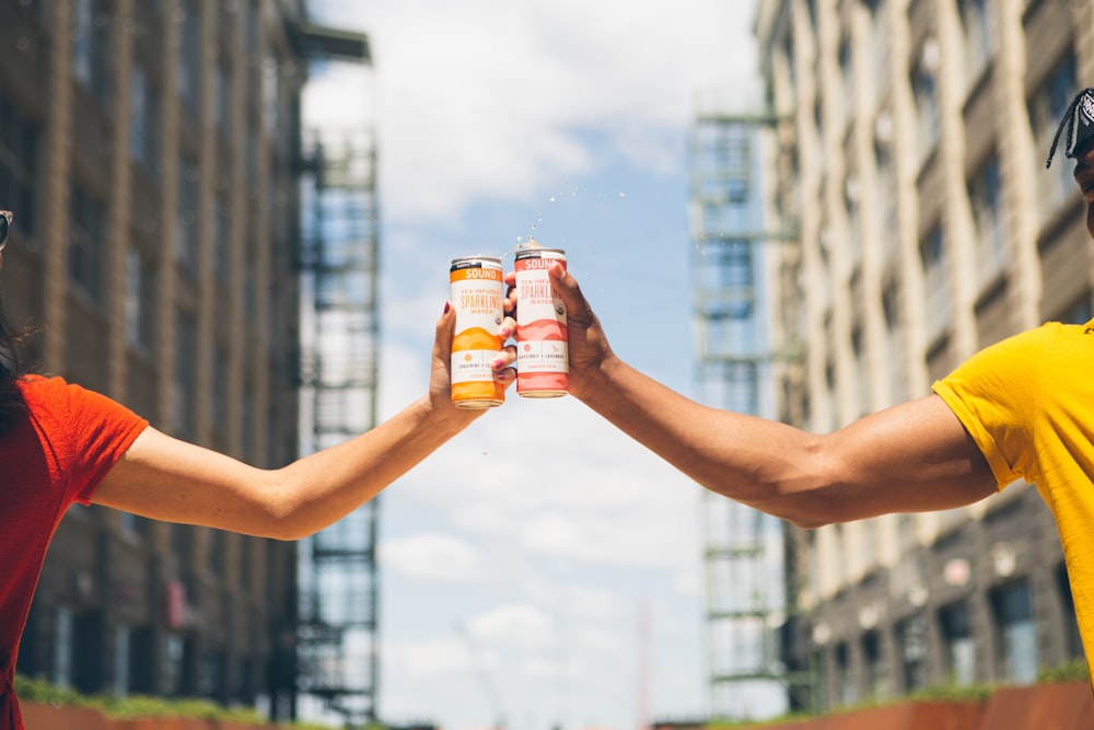 homme et femme tenant des canettes de soda