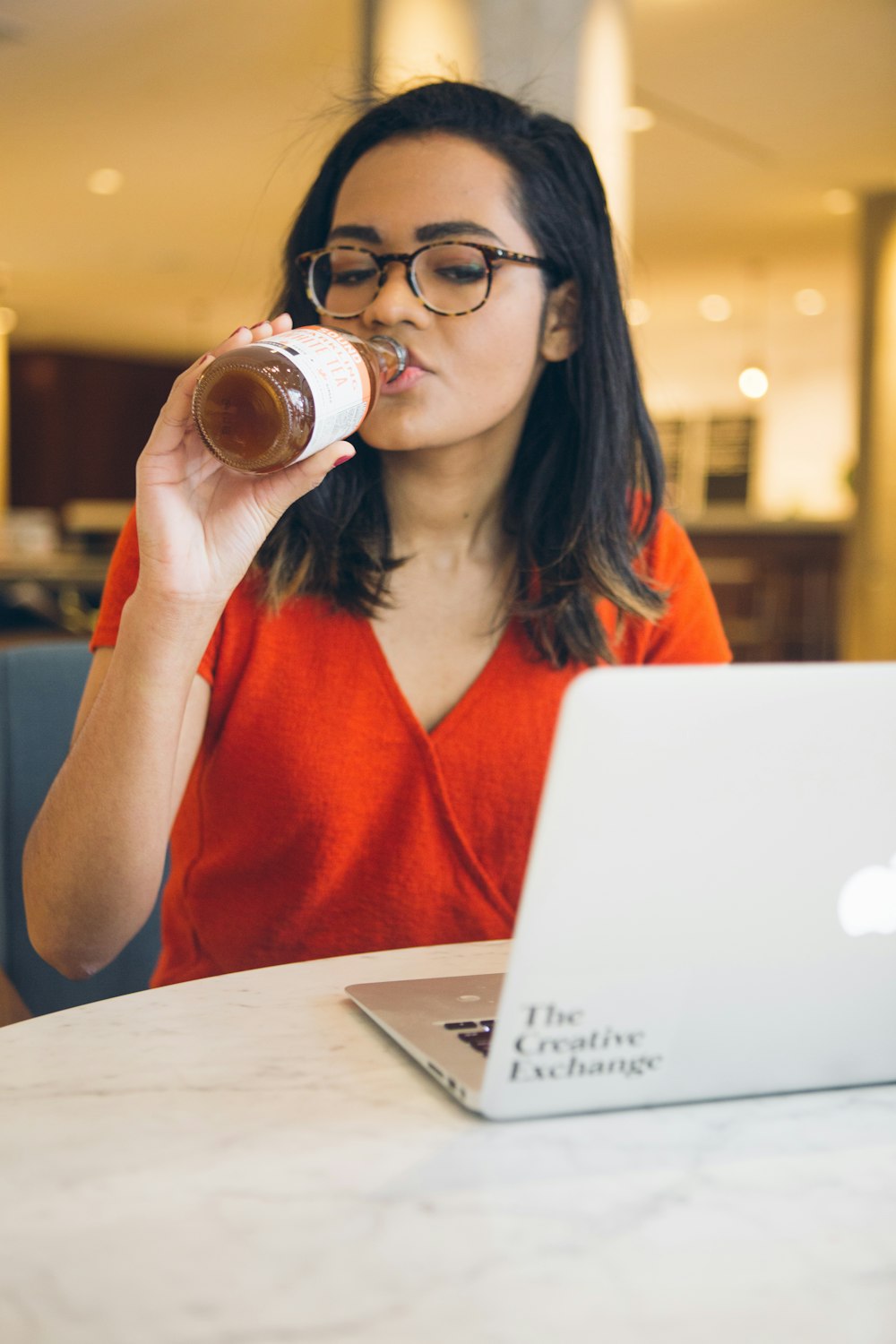 woman sitting beside white table while drinking liquid