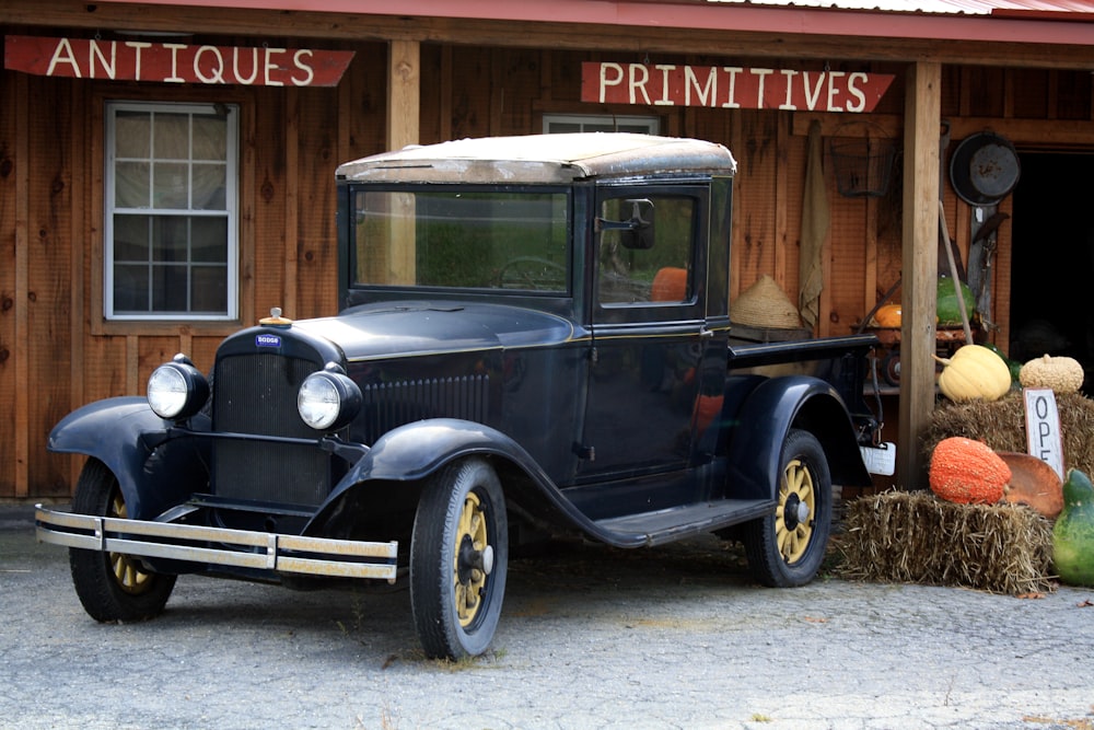 classic black vehicle parked beside brown house