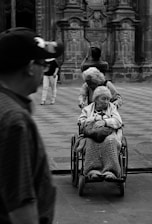 grayscale photography unknown person riding on wheelchair outdoors