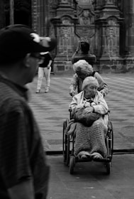 grayscale photography unknown person riding on wheelchair outdoors